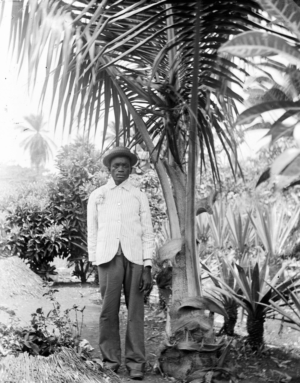 a man standing next to a palm tree