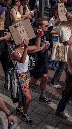 a woman holding a cardboard sign with a smiley face drawn on it