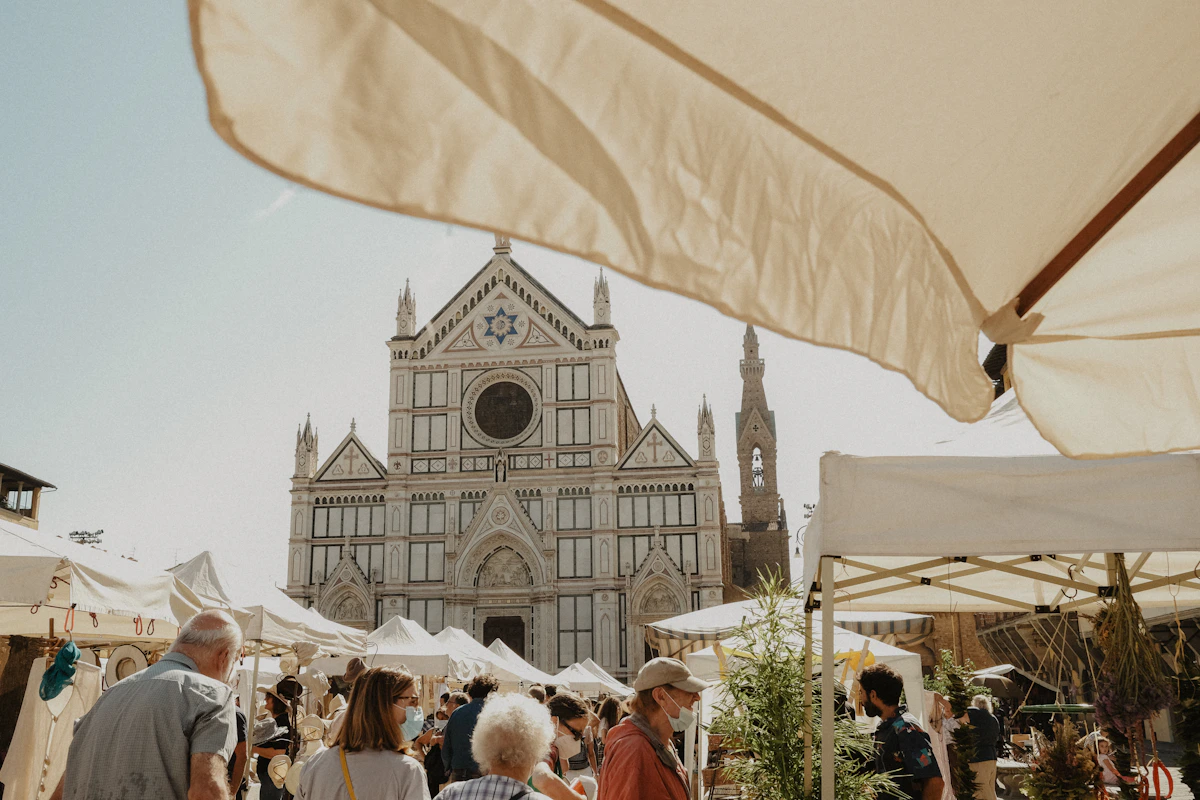 People browsing produce stalls at a local outdoor market in Florence
