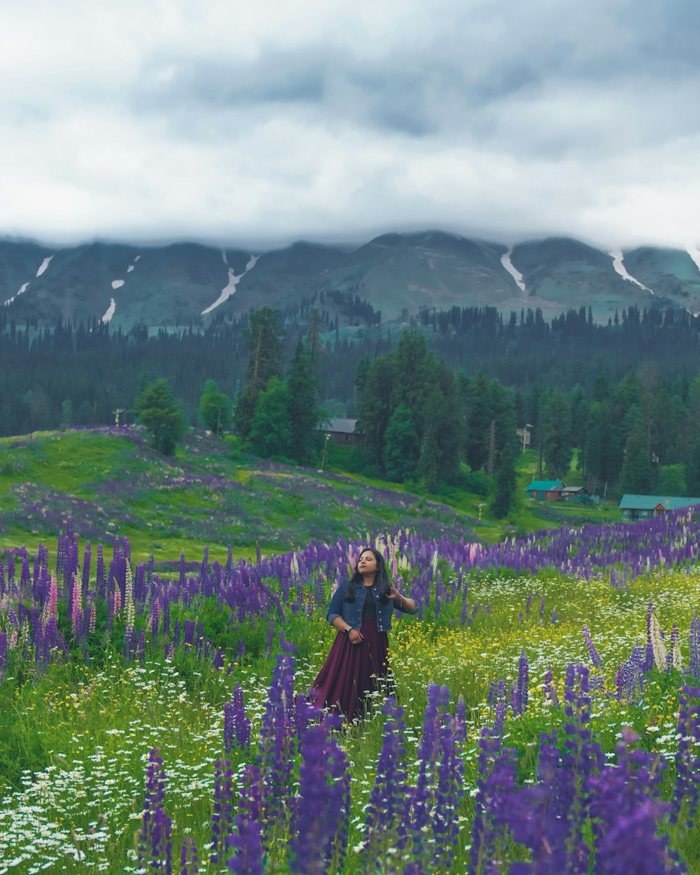 uma mulher de pé em um campo de flores roxas