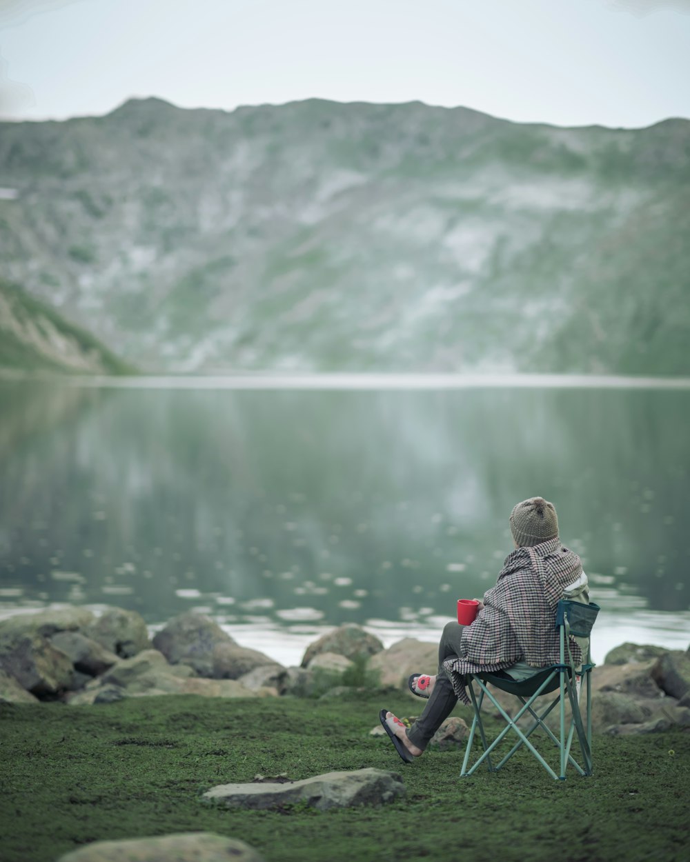 a person sitting in a chair near a body of water