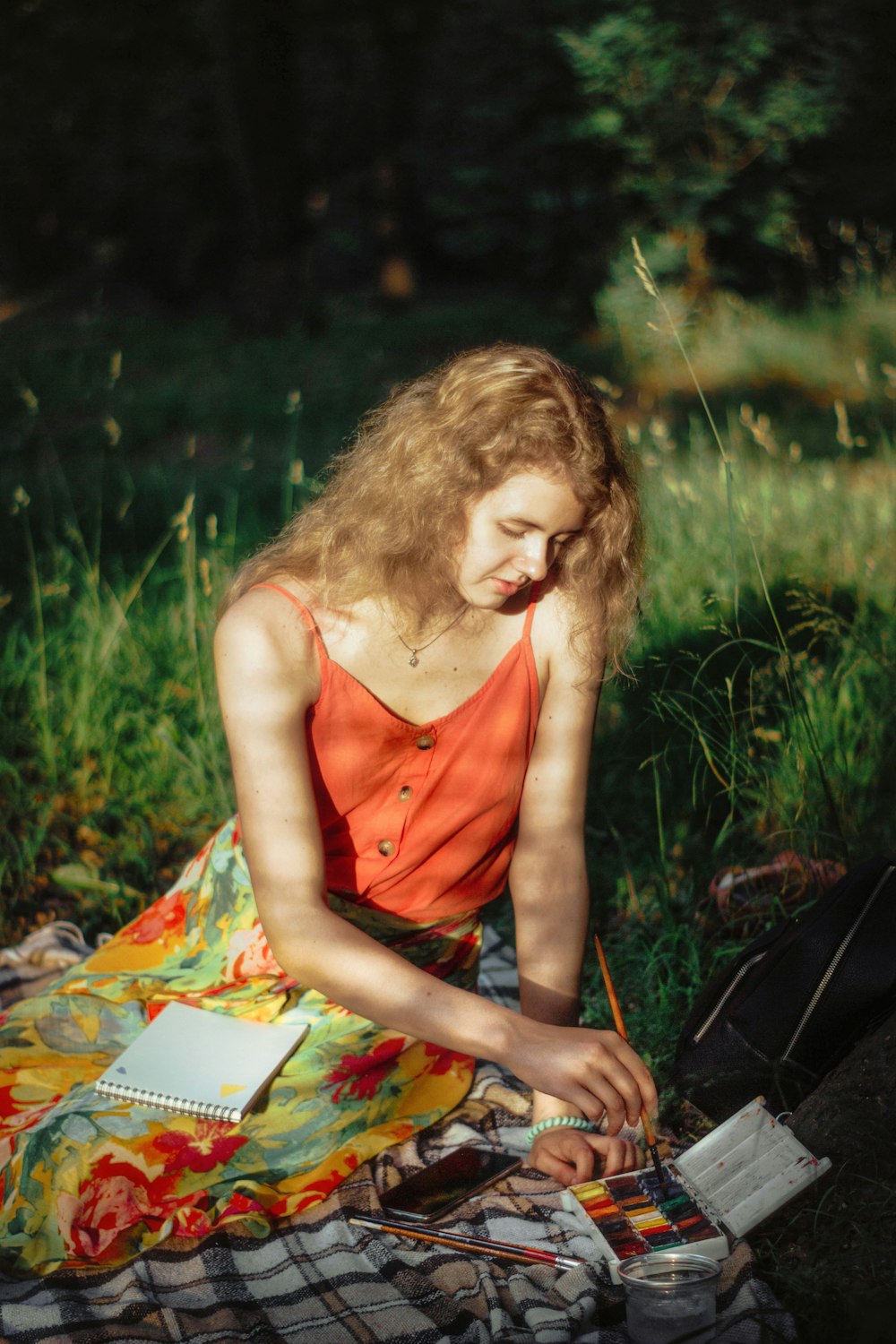 a woman sitting on a blanket in the grass