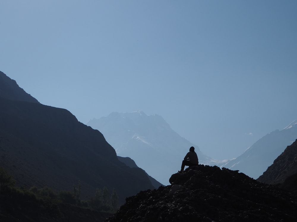 a person sitting on top of a large rock