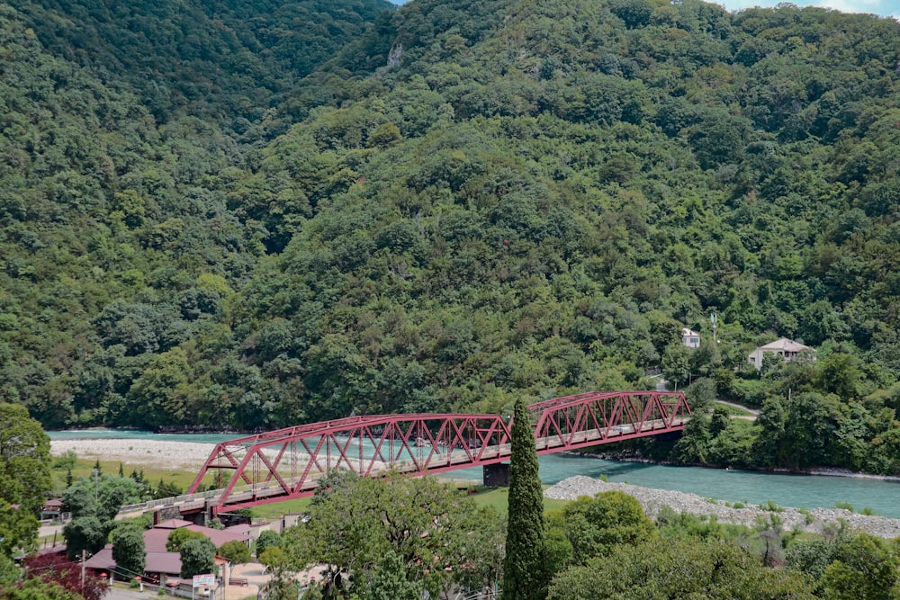 a red bridge over a river surrounded by trees