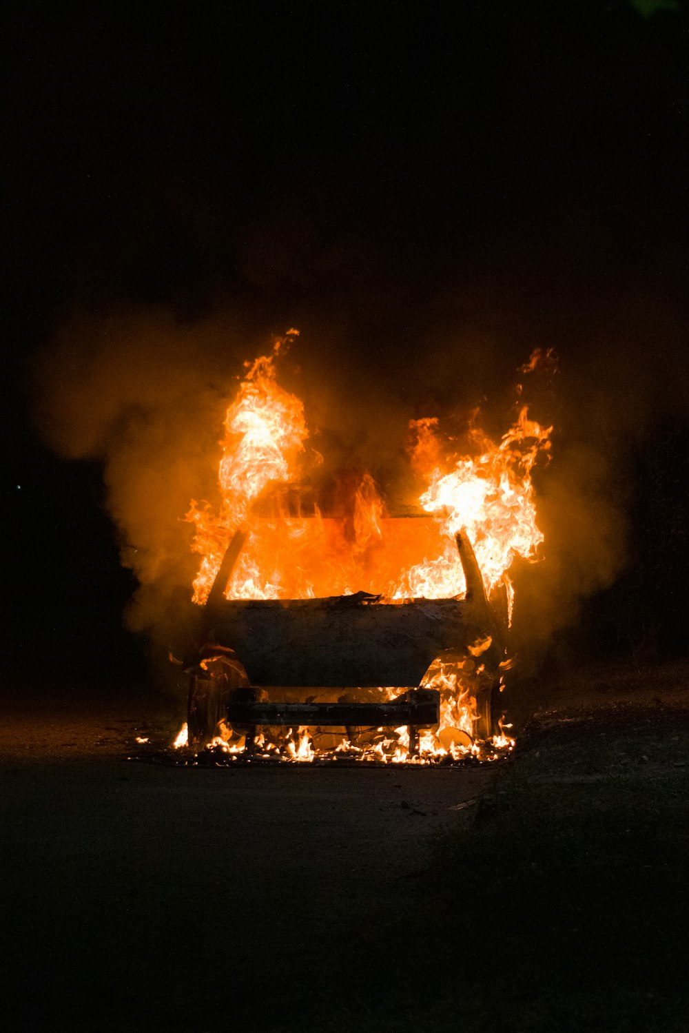 a fire burning in the dark with a bench in front of it