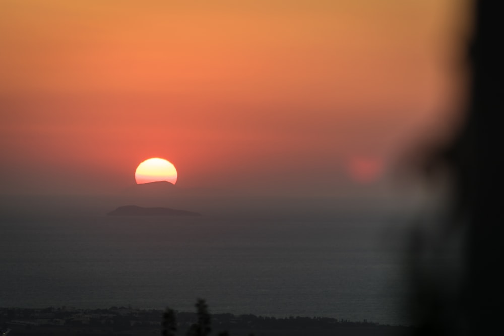 the sun is setting over the horizon of a body of water