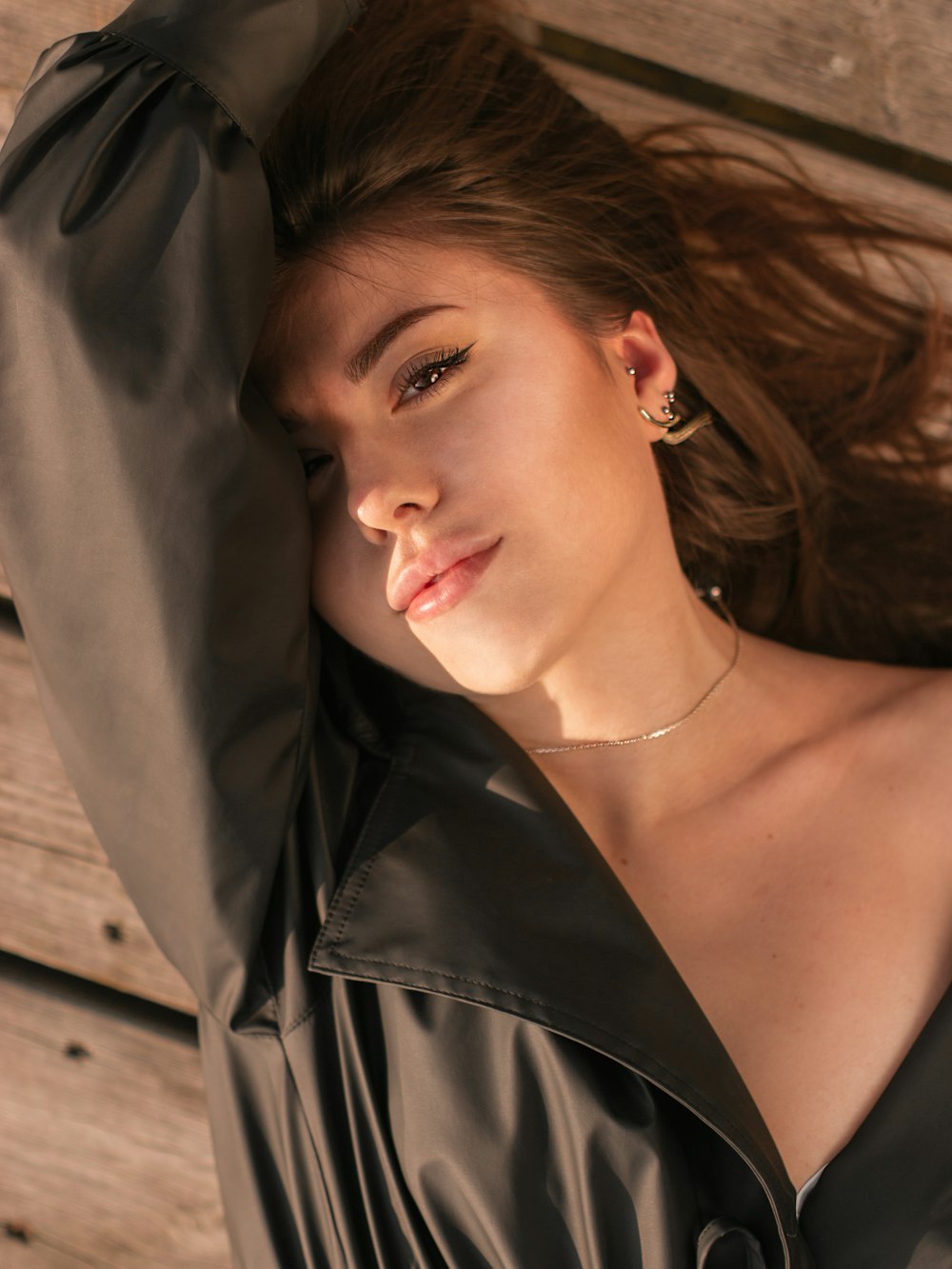 a woman in a black dress laying on a wooden bench