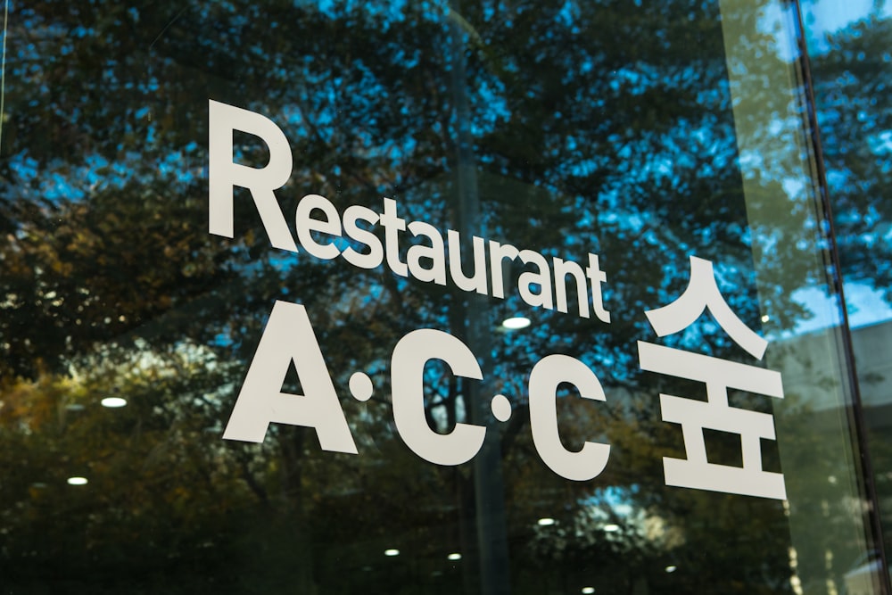 a restaurant sign on a glass door with trees in the background