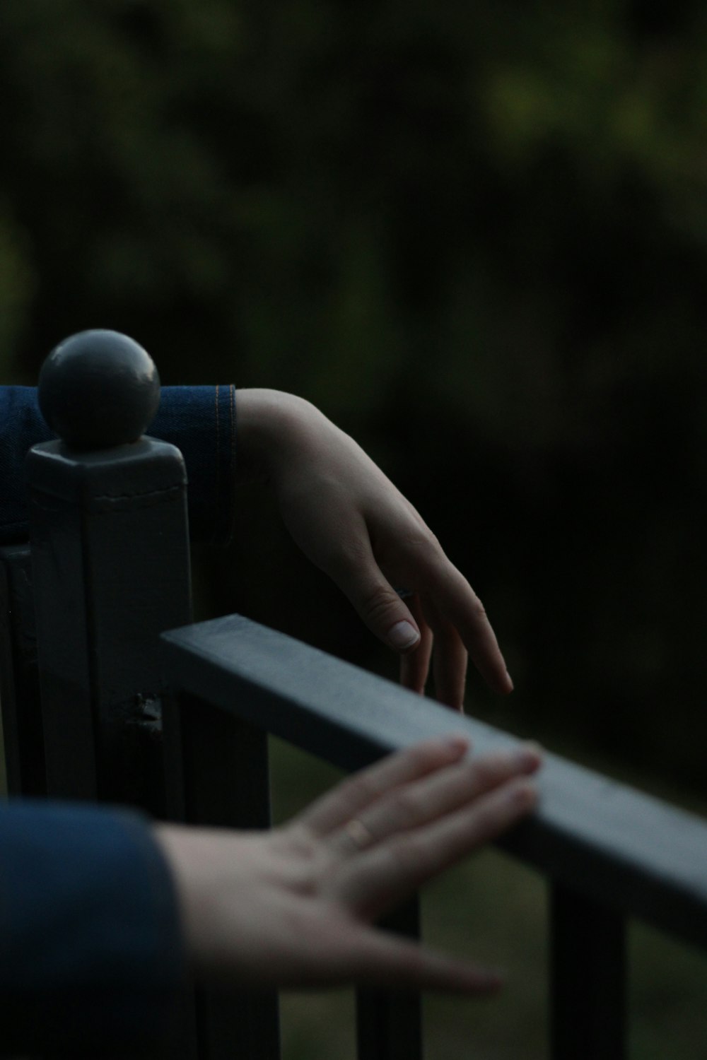 a hand reaching over a railing towards a person's hand