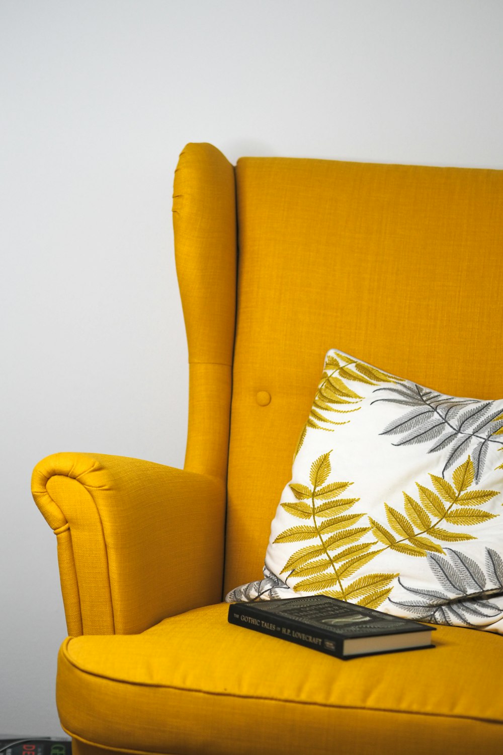 a yellow chair with a pillow and a book on it