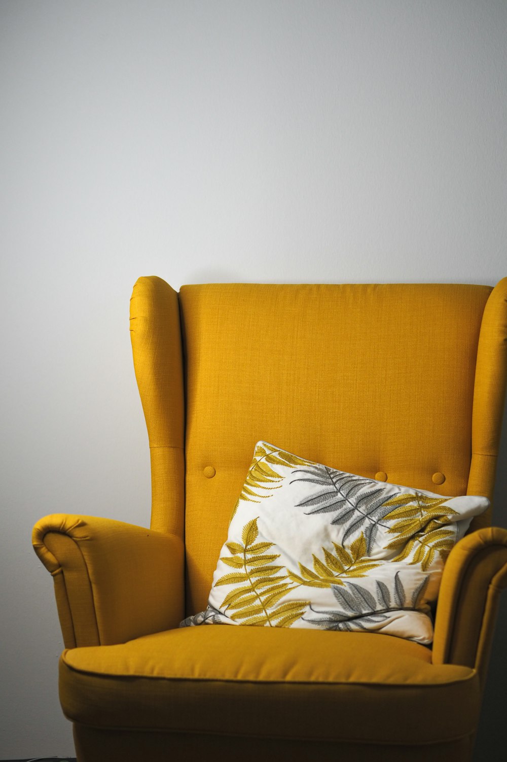 a yellow chair with a pillow on top of it
