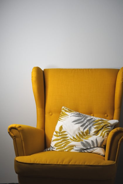 a yellow chair with a pillow on top of it photo – Free Brown Image on  Unsplash