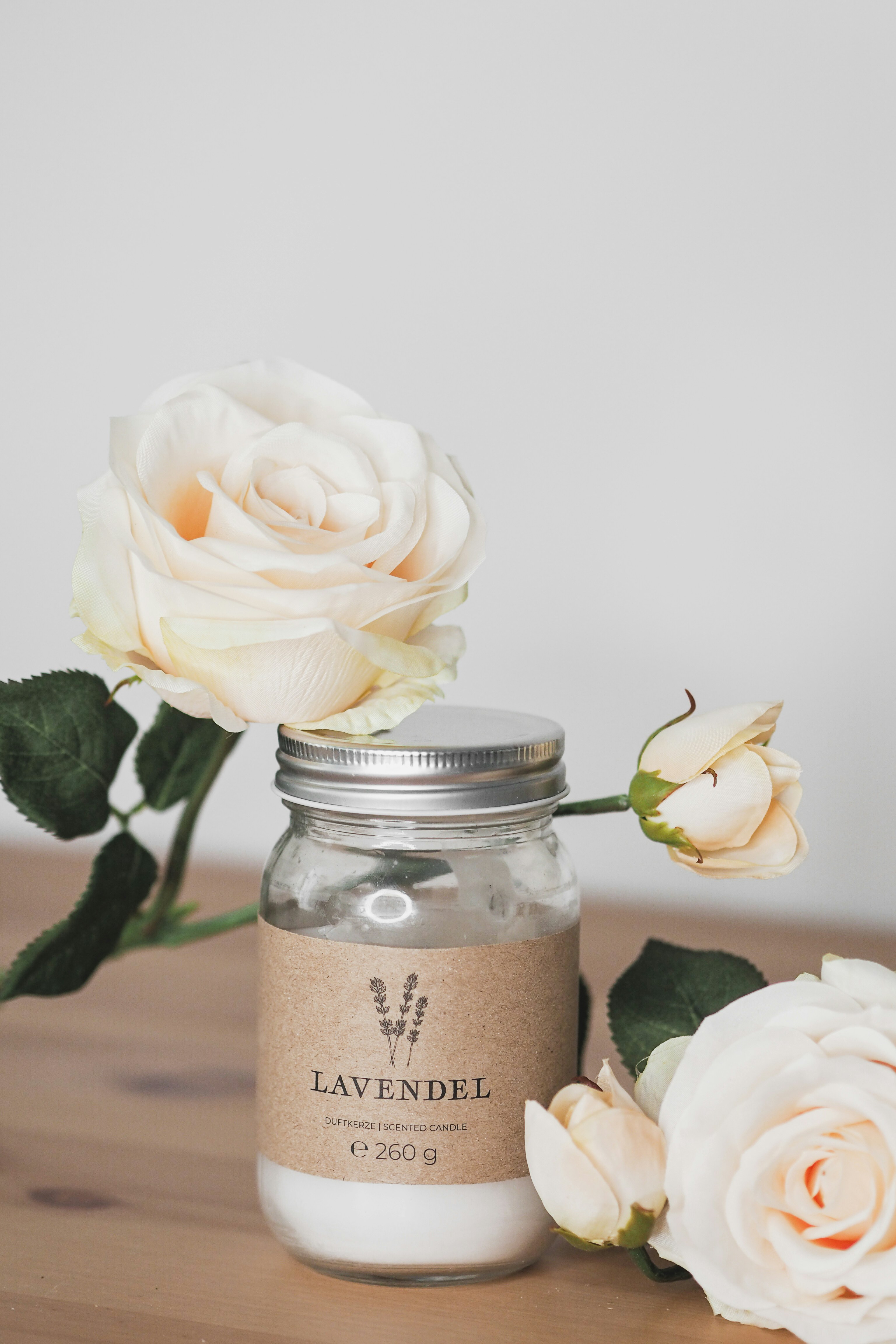 Rich cream in dark glass jar with lavender sprigs on navy surface — moody dim atmospheric lighting