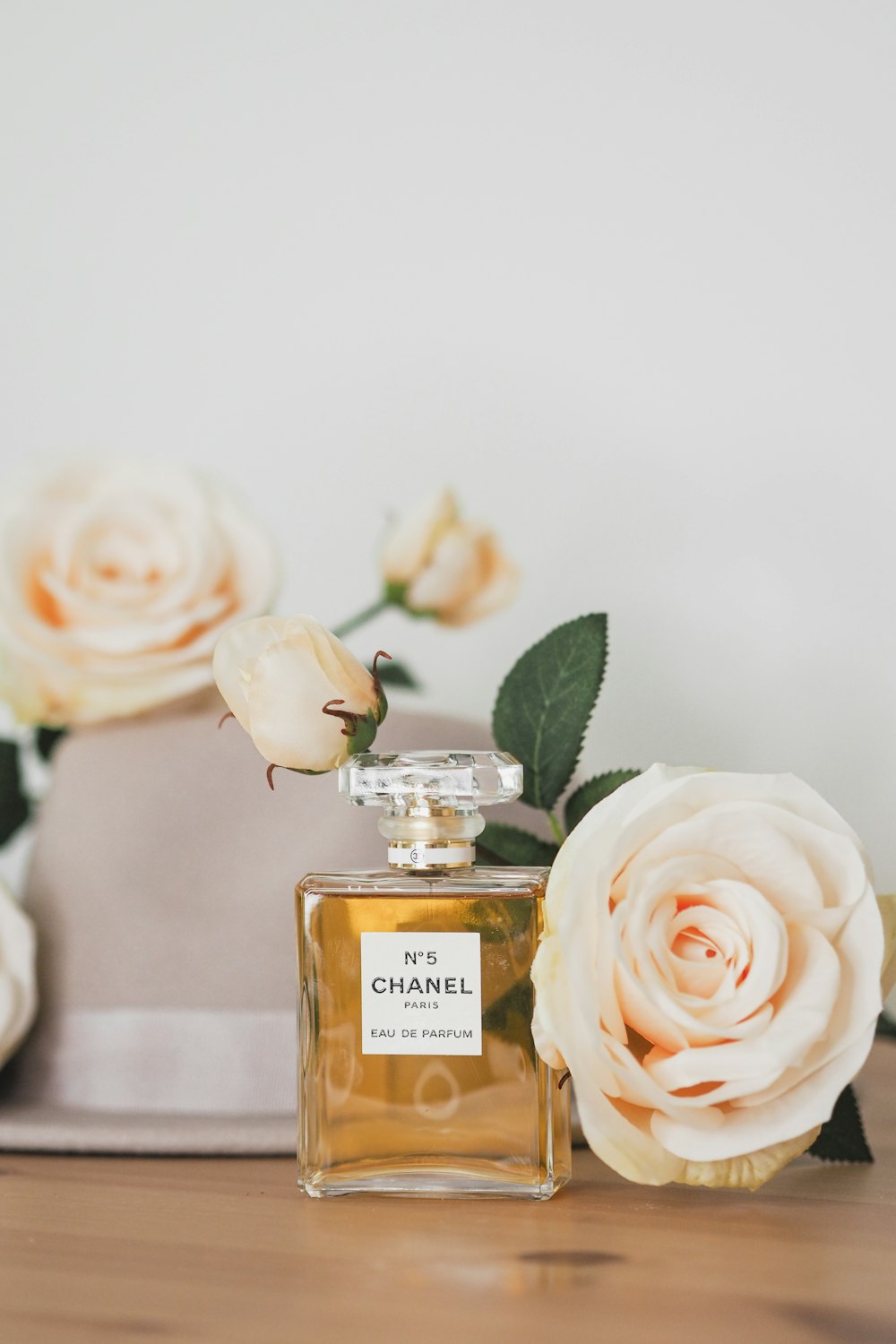 a bottle of chanel perfume sitting on a table next to flowers