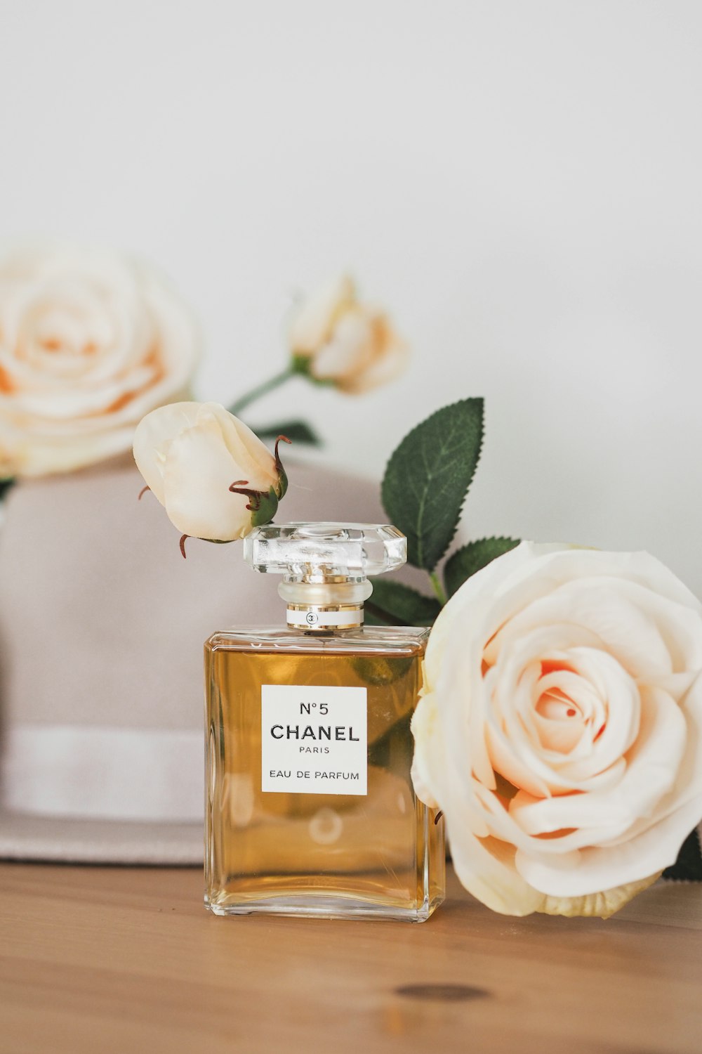 A bottle of chanel perfume sitting on a table next to flowers