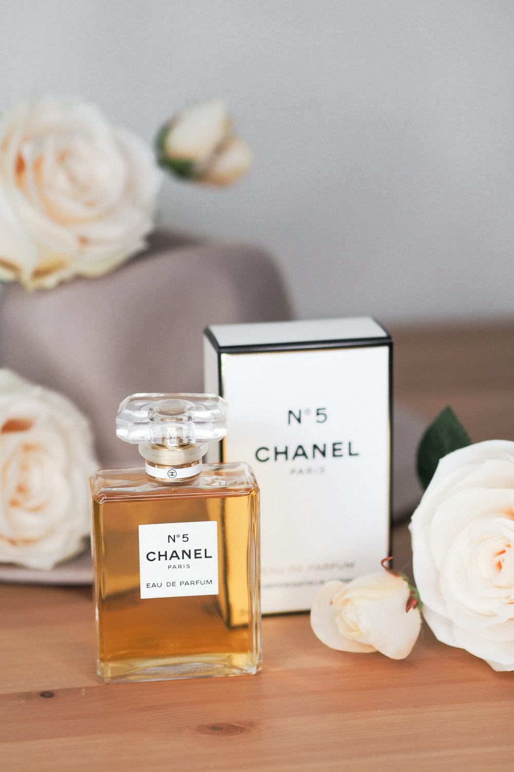 A bottle of chanel perfume next to a box of flowers photo – Free Grey Image  on Unsplash
