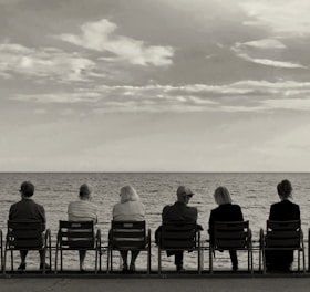 a group of people sitting on top of a beach next to the ocean