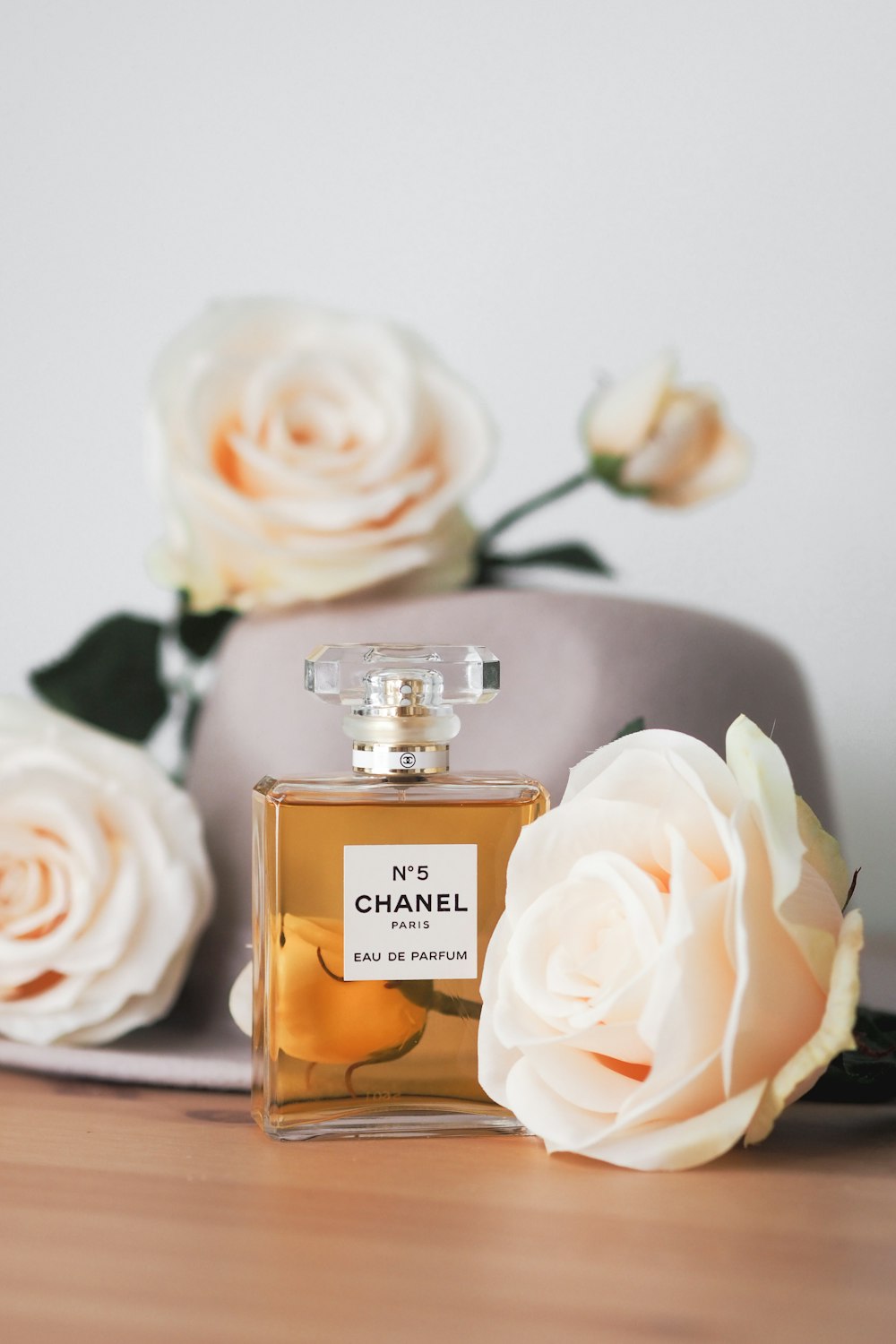 a bottle of chanel perfume next to a hat and flowers