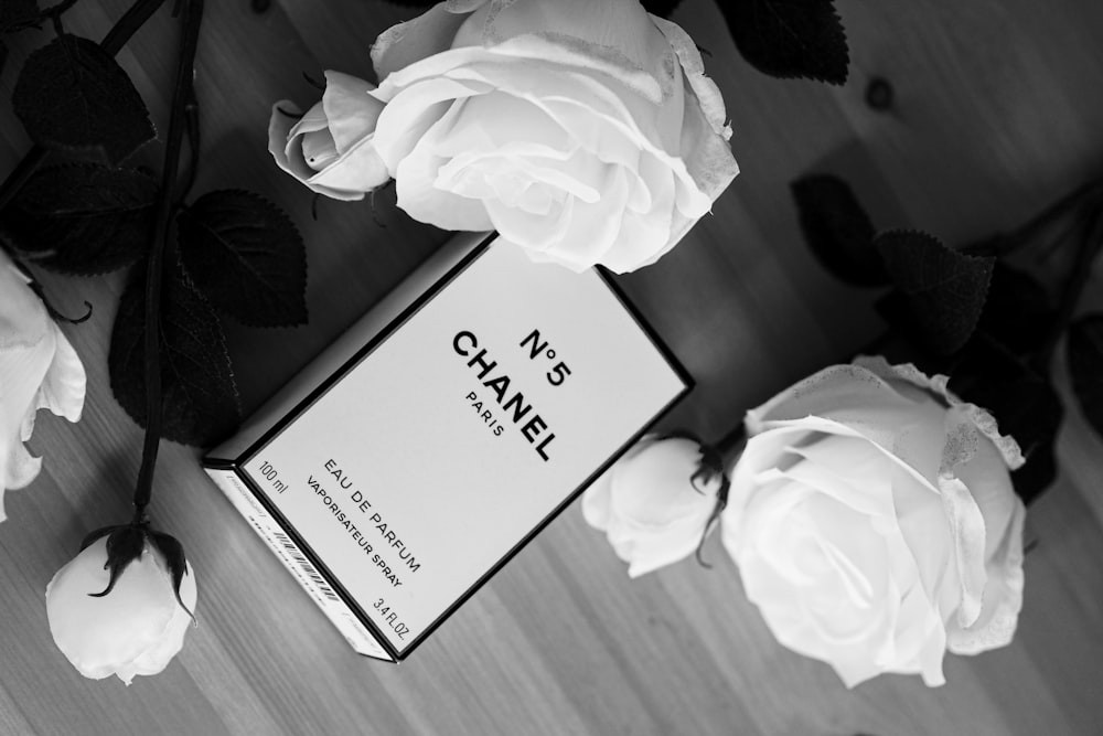 A bottle of chanel perfume next to a hat and flowers photo – Free