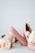 Close-up of a pair of elegant blush pink heels resting on a soft beige fabric background.