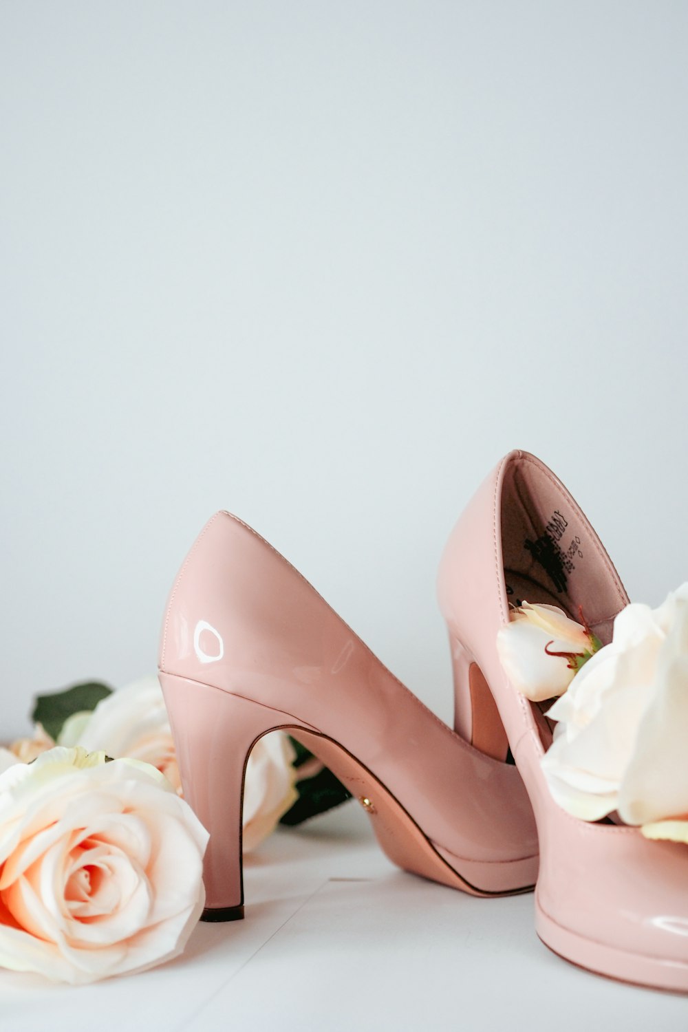 a pair of pink high heeled shoes next to a bouquet of roses