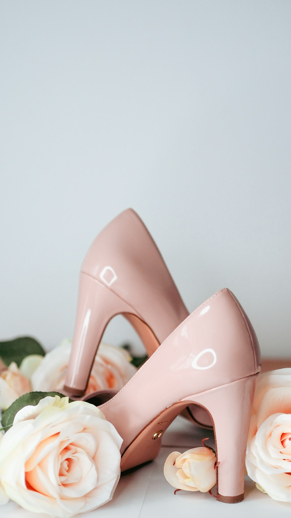 a pair of pink high heeled shoes next to roses