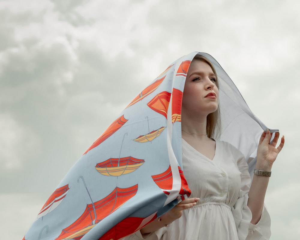 a woman in a white dress holding a blue and orange umbrella