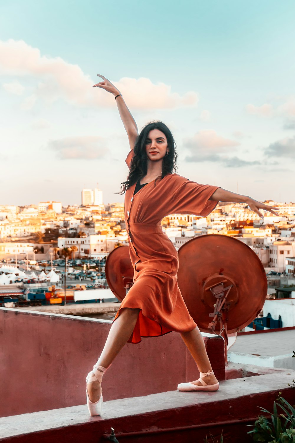 a woman standing on a ledge with her arms outstretched