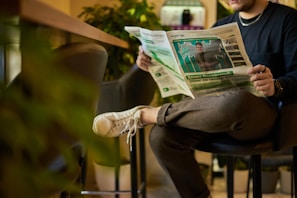 a man sitting in a chair reading a newspaper