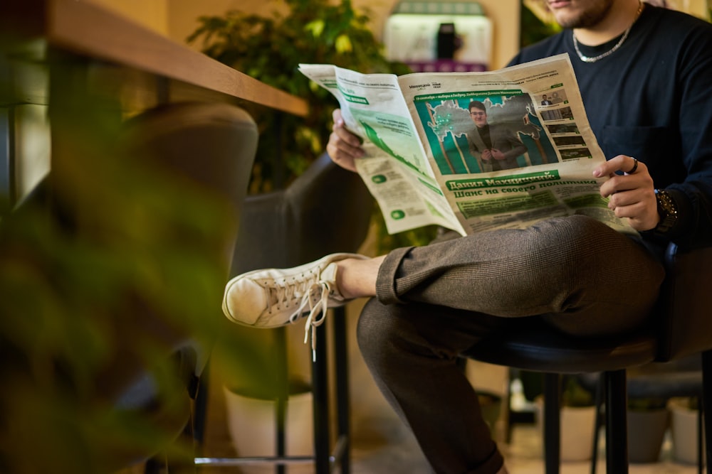 a man sitting in a chair reading a newspaper