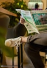 a man sitting in a chair reading a newspaper