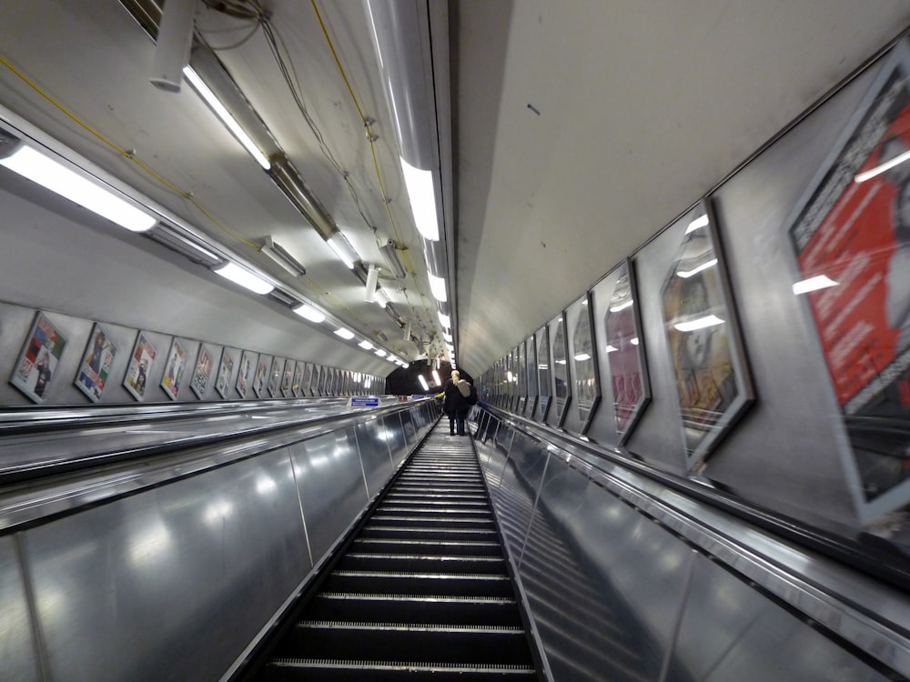 un escalier roulant dans une station de métro avec des gens à bord