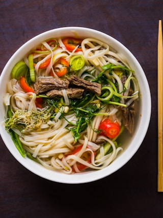 a bowl of noodle soup with chopsticks on the side