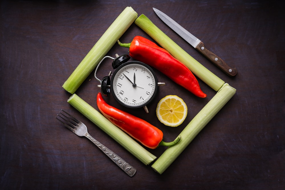 a clock surrounded by vegetables and a knife