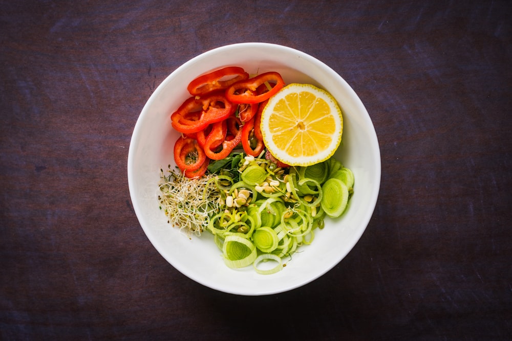 a white bowl filled with vegetables and sliced oranges