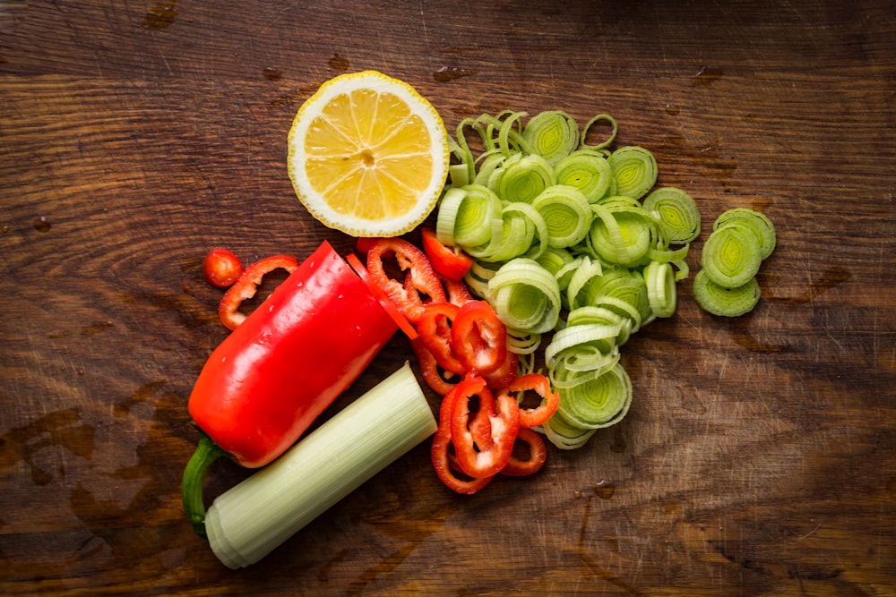 a wooden table topped with sliced vegetables and a lemon