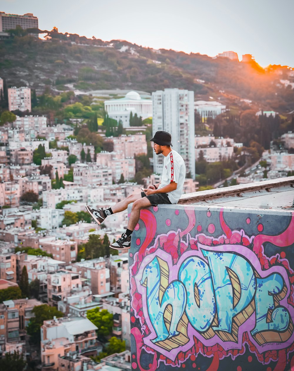 um jovem sentado em cima de uma parede coberta de grafite