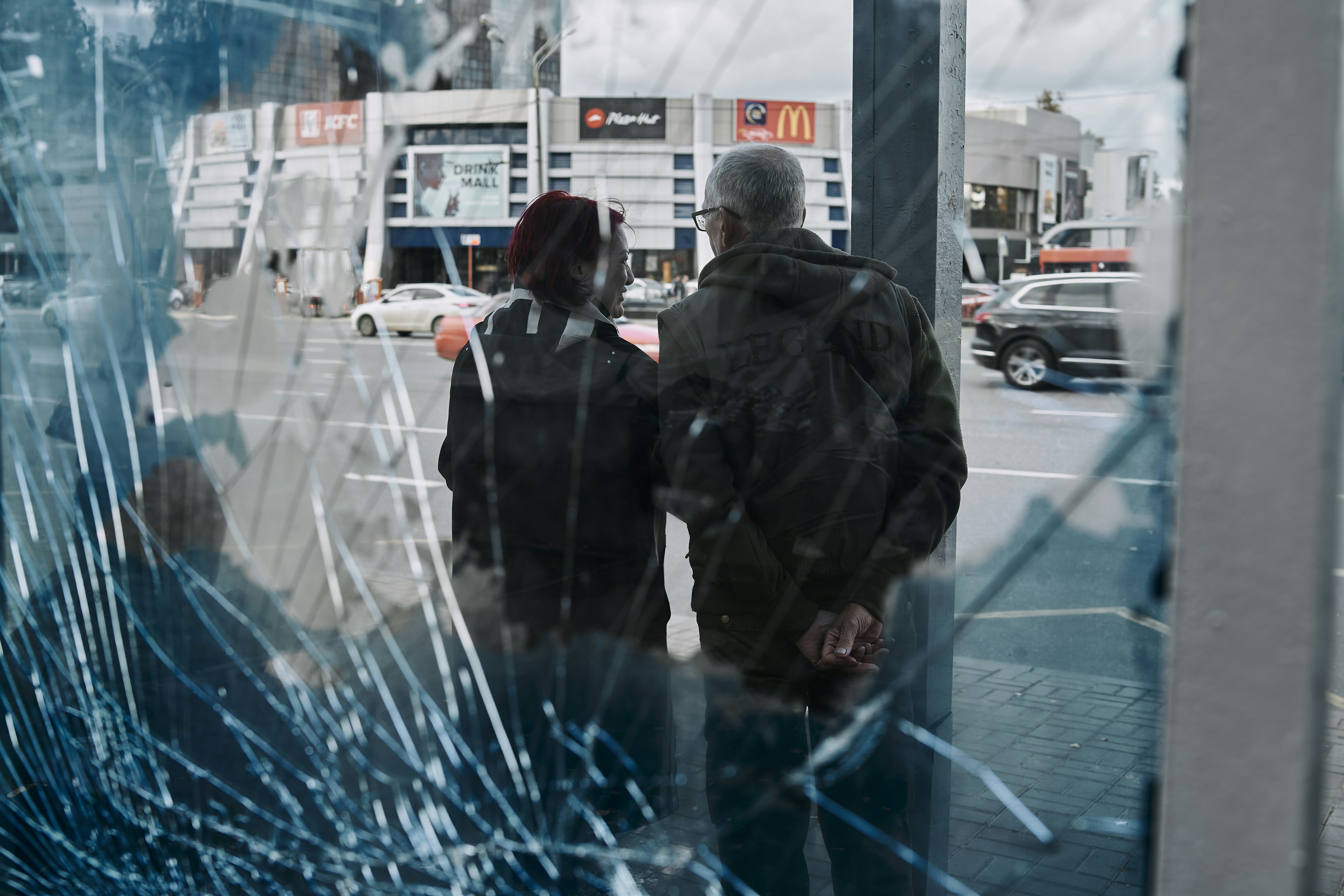 a man and a woman standing in front of a broken window