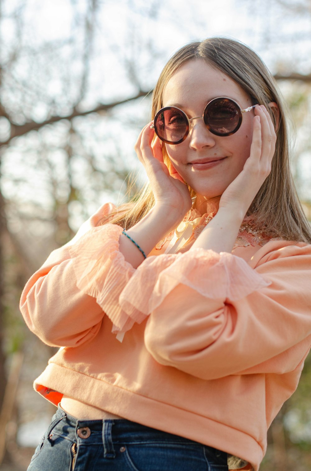 a woman in a pink shirt and sunglasses talking on a cell phone