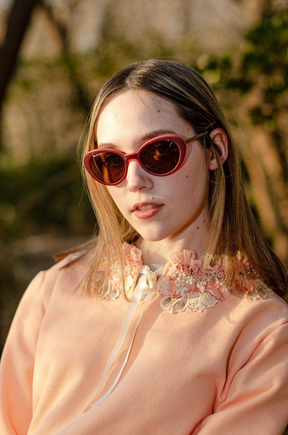 Una mujer con gafas de sol y una camisa rosa