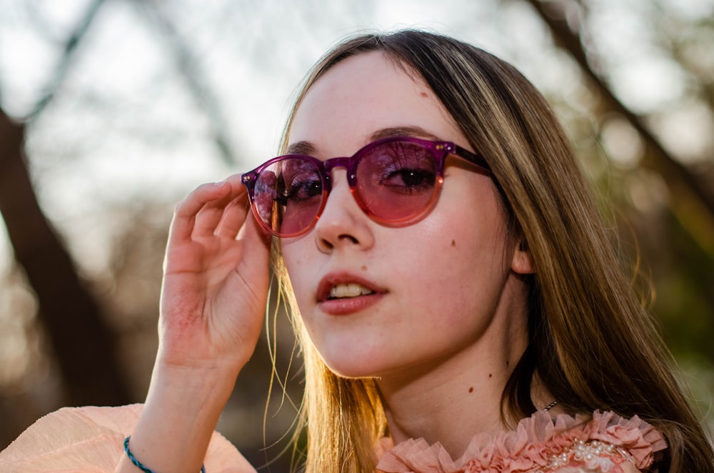 a young woman wearing sunglasses and a pink dress