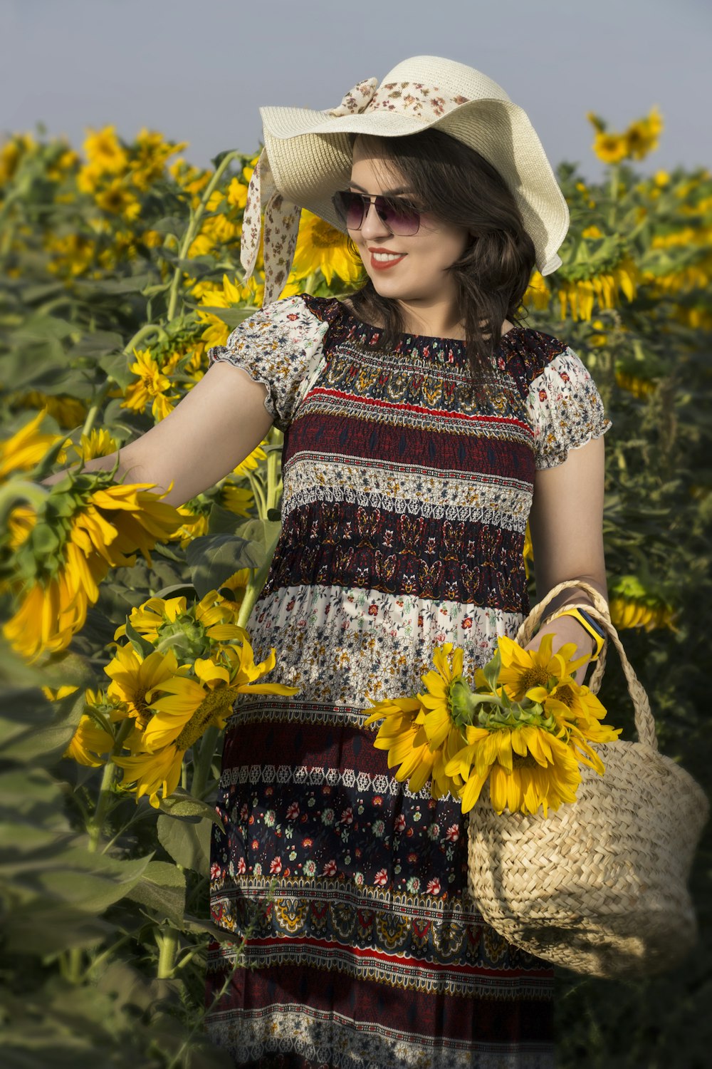a woman in a sunflower field holding a basket of sunflowers