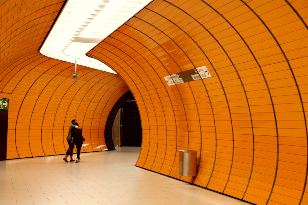 a man standing in a subway station next to a yellow wall