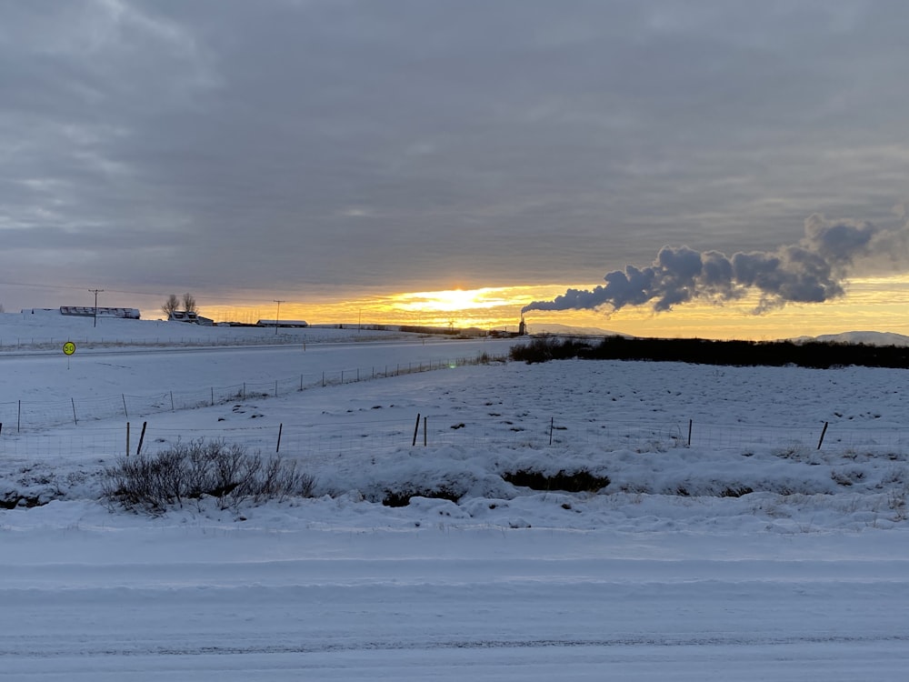 a snow covered field with a factory in the distance