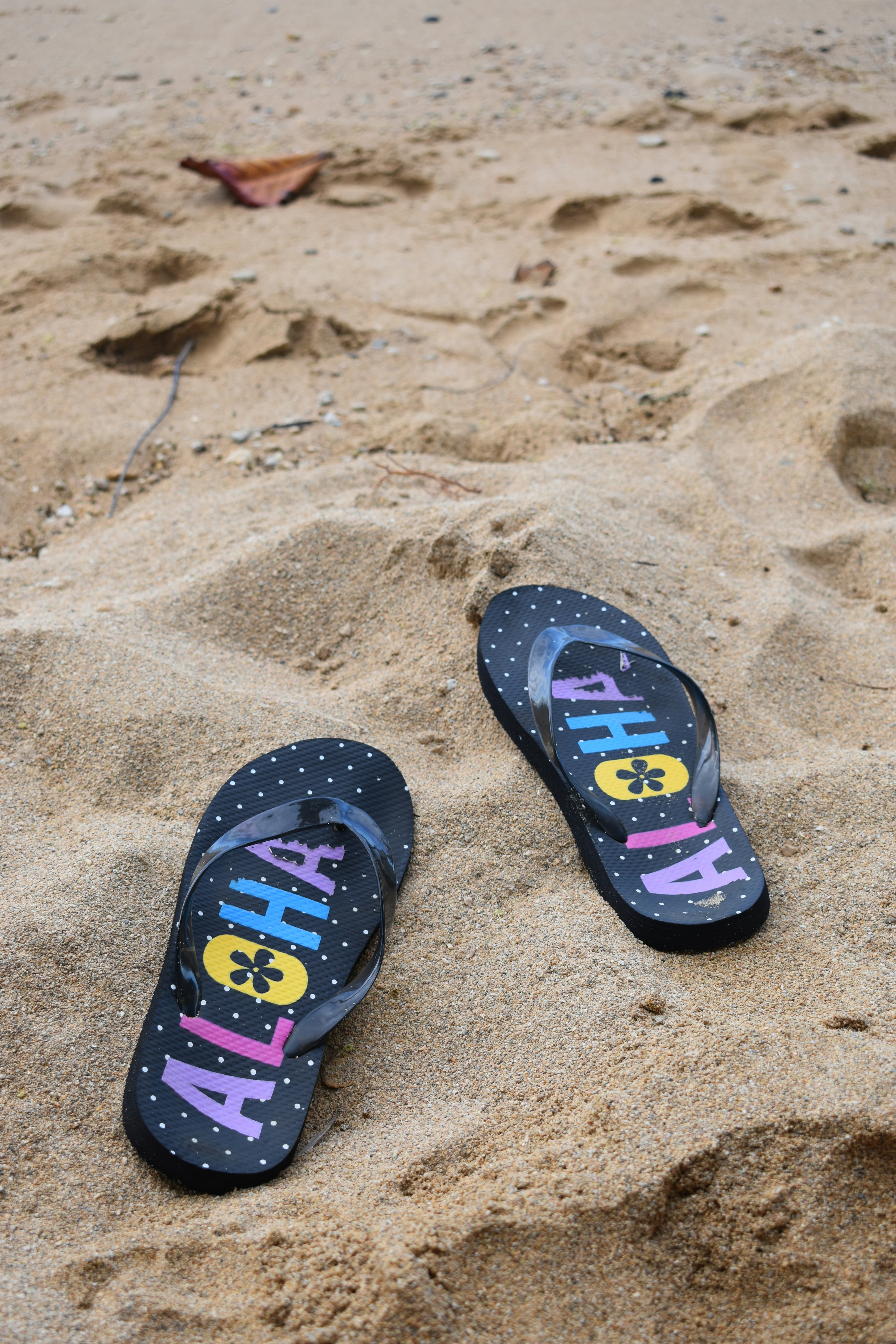 a pair of flip flops sitting on top of a sandy beach