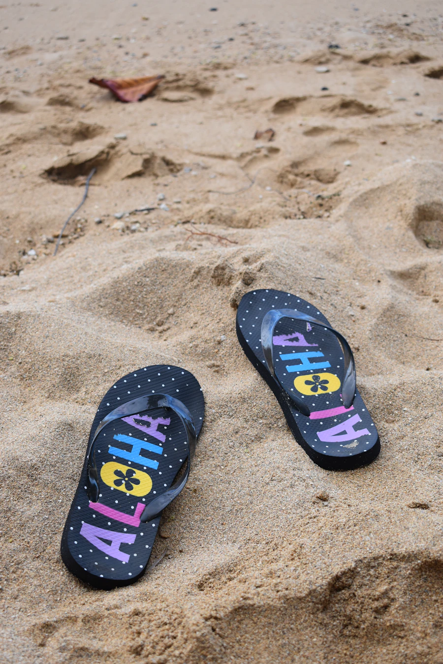 Pair of flip-flops resting on sandy beach, representing a pared-down beach vacation packing list