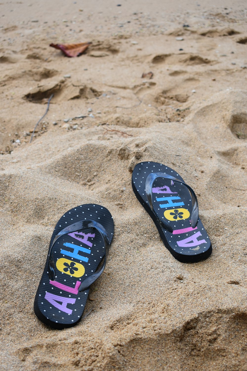 a pair of flip flops sitting on top of a sandy beach