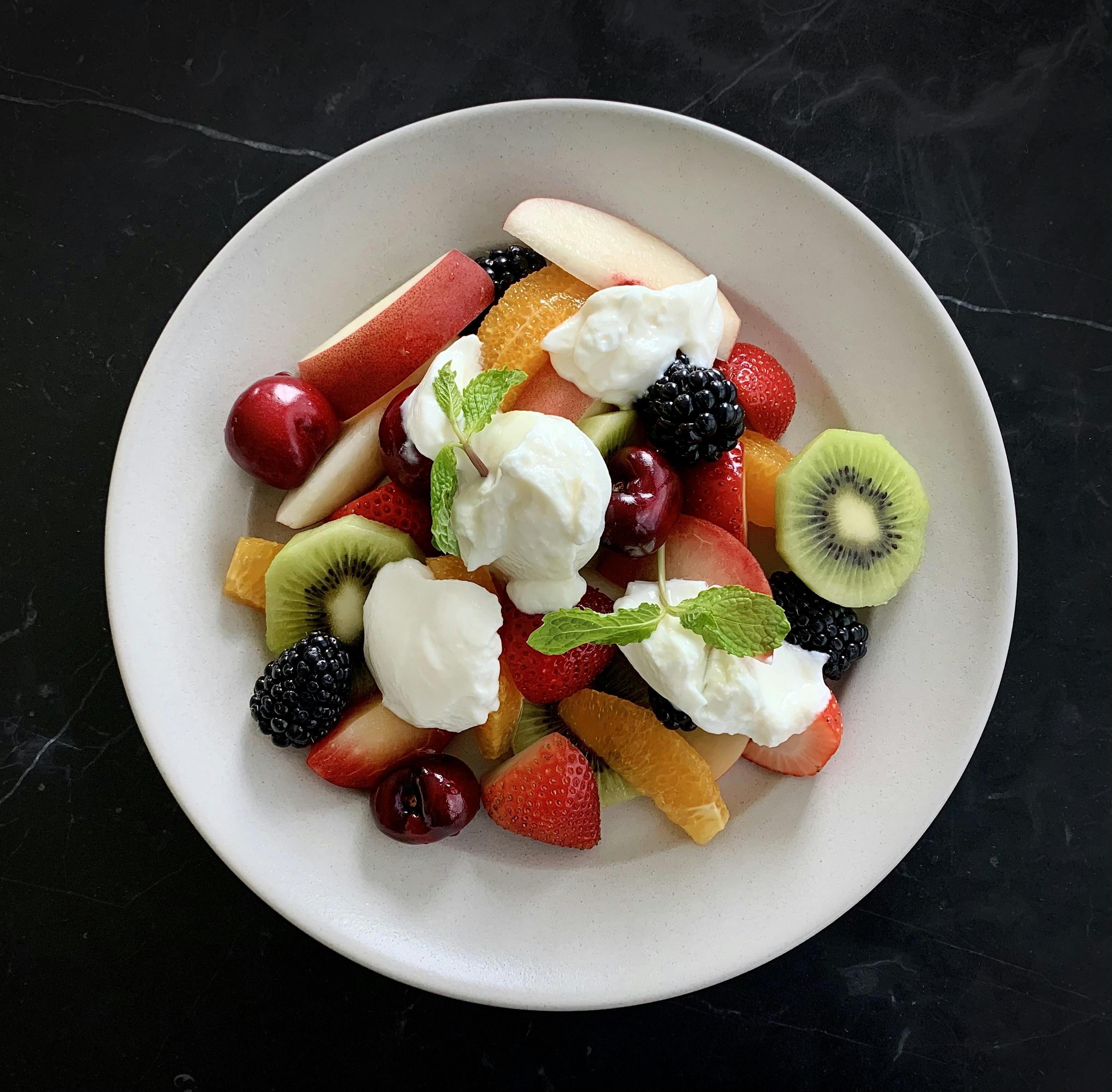 a white plate topped with fruit and whipped cream