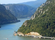 A serene river winding through rugged terrain with colorful local boats tied along the shore.