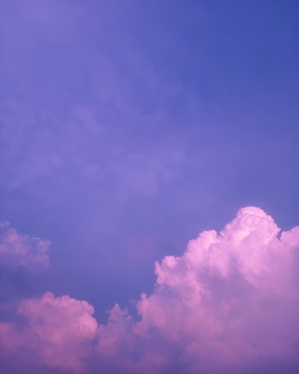 a plane flying through a blue cloudy sky